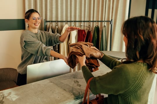 A woman returning clothes to a cashier instore